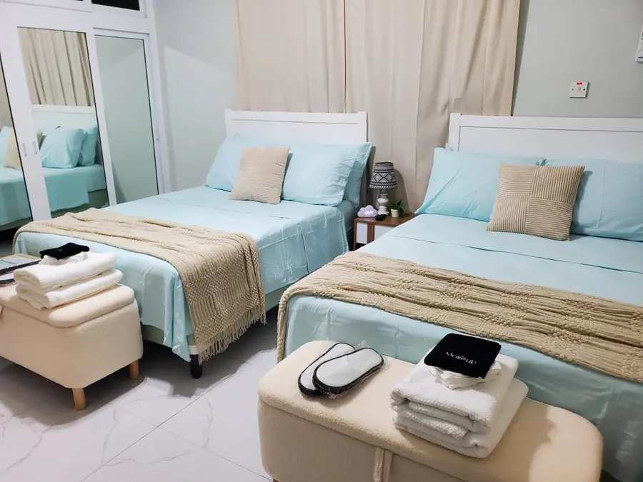 Third bedroom with two double beds in sand and sky-blue linens