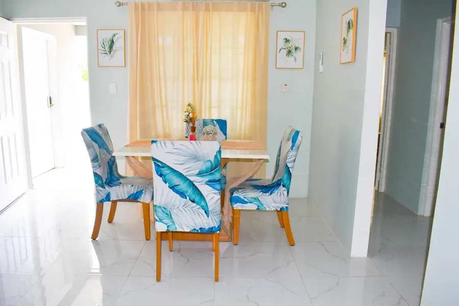 Dining area with four chairs upholstered in a palm-leaf print