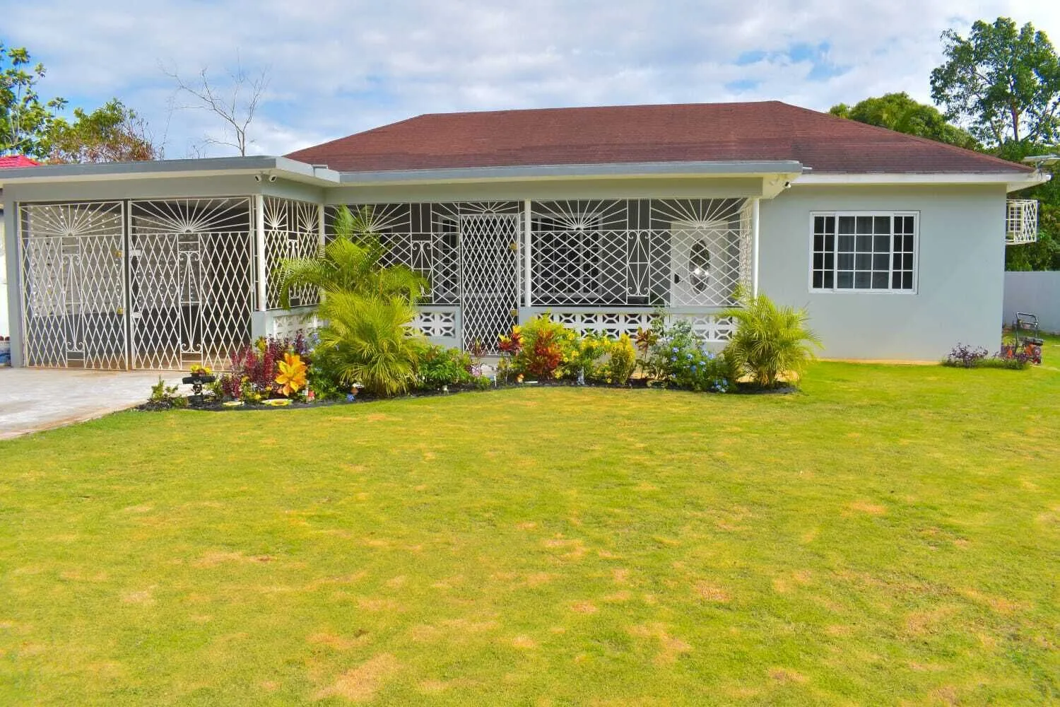 Coral House seen across its front lawn, a single-storey white villa with a terracotta roof