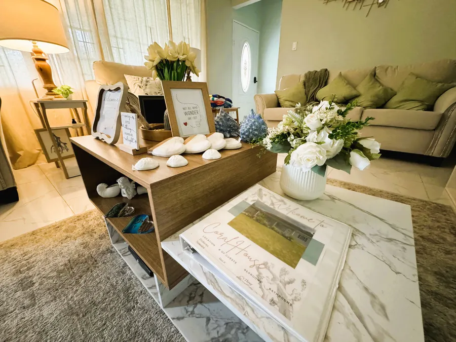 Open-plan living room with a soft sofa, marble-topped coffee table and fresh white flowers